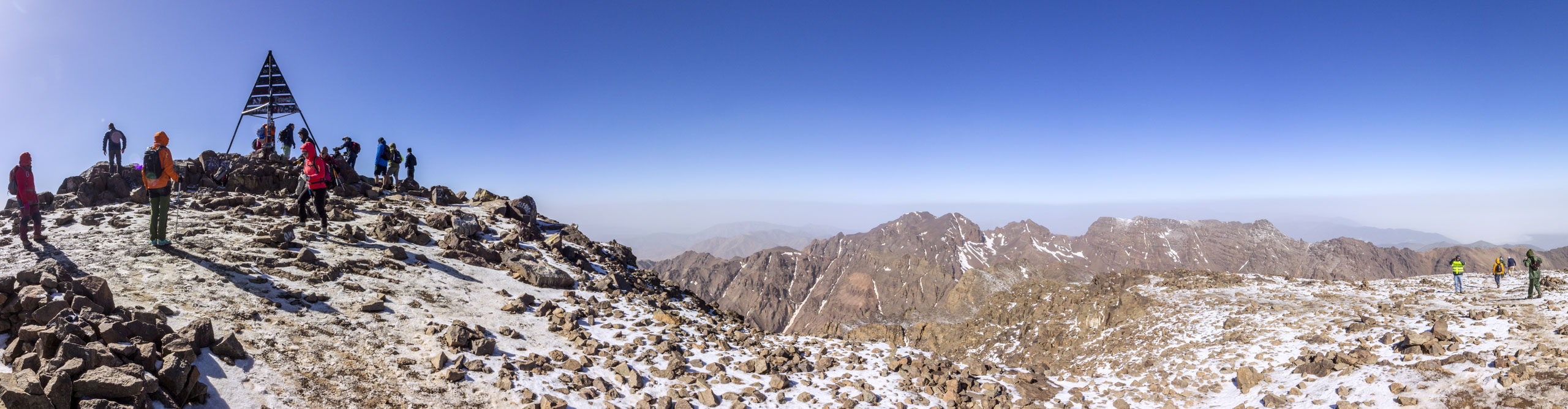 Intrepid travellers at the peak of Mount Toubkal and look out over the High Atlas Mountains