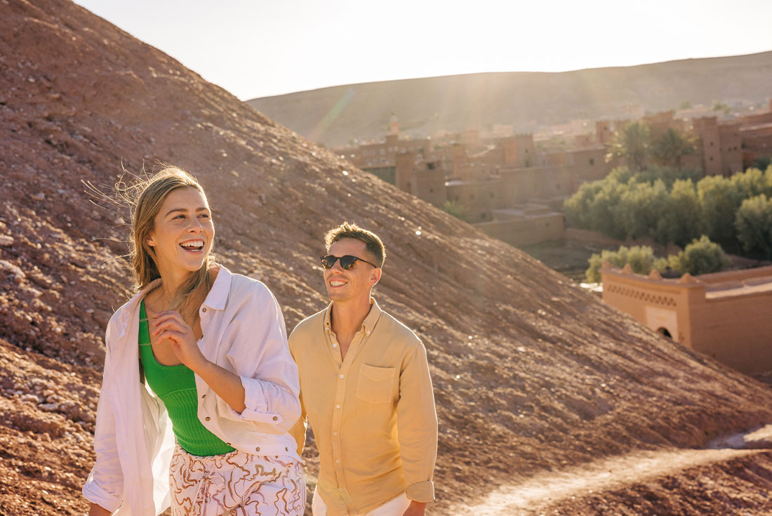 Travellers walking through Ait Benhaddou with mountains background, Morocco