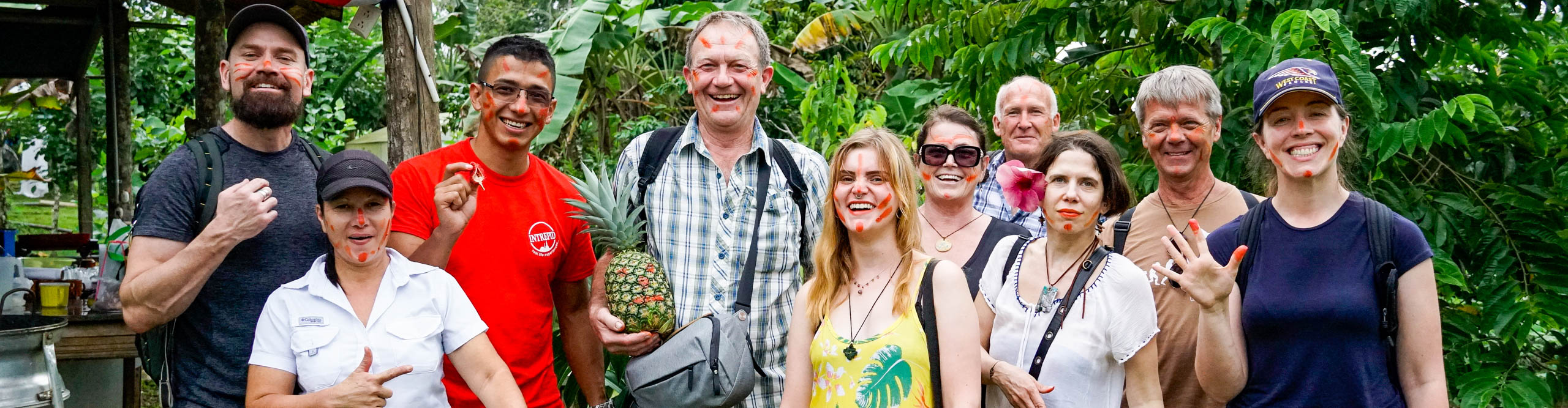Group smiling at camera, with painted faces and holding pineapples, Costa Rica 