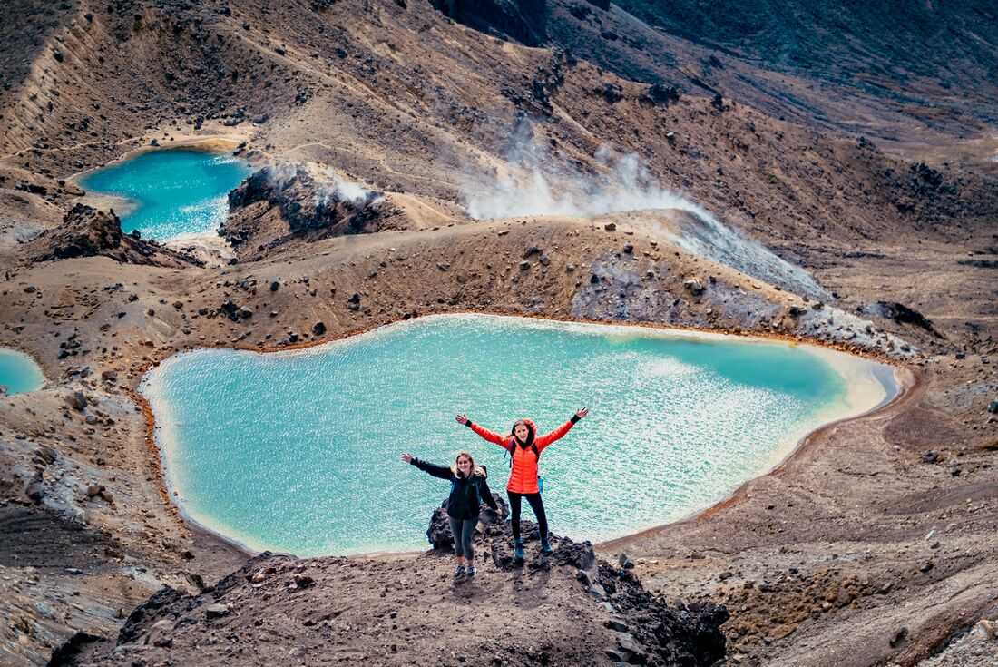 Intrepid Travellers stop to pose with the bright blue geothermal pools in Tongariro