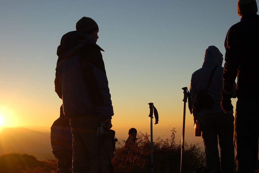 Trekkers pause to take in the mountains amidst the light of the sunrise