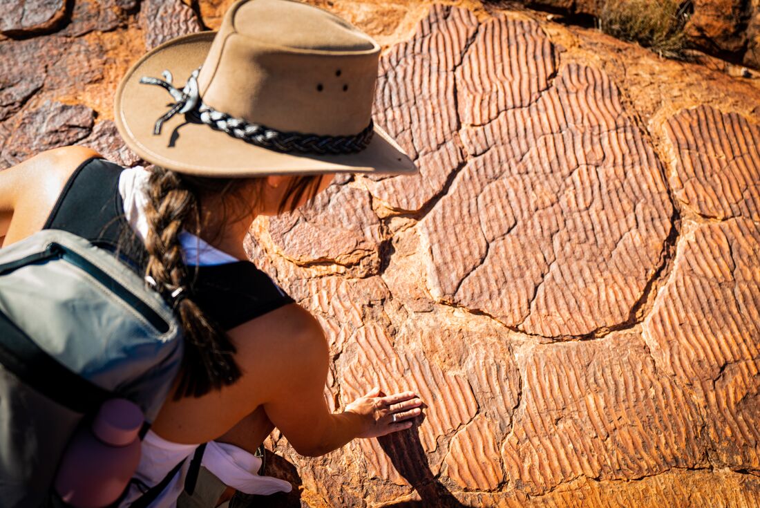 Traveller touching textured rocks in Red Centre, Australia