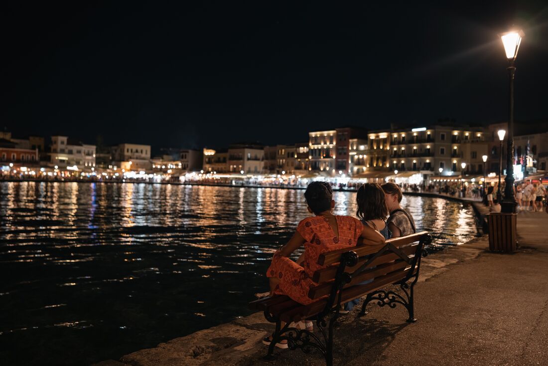 Group of Intrepid travellers and leader relax harbourside in Chania in the evening