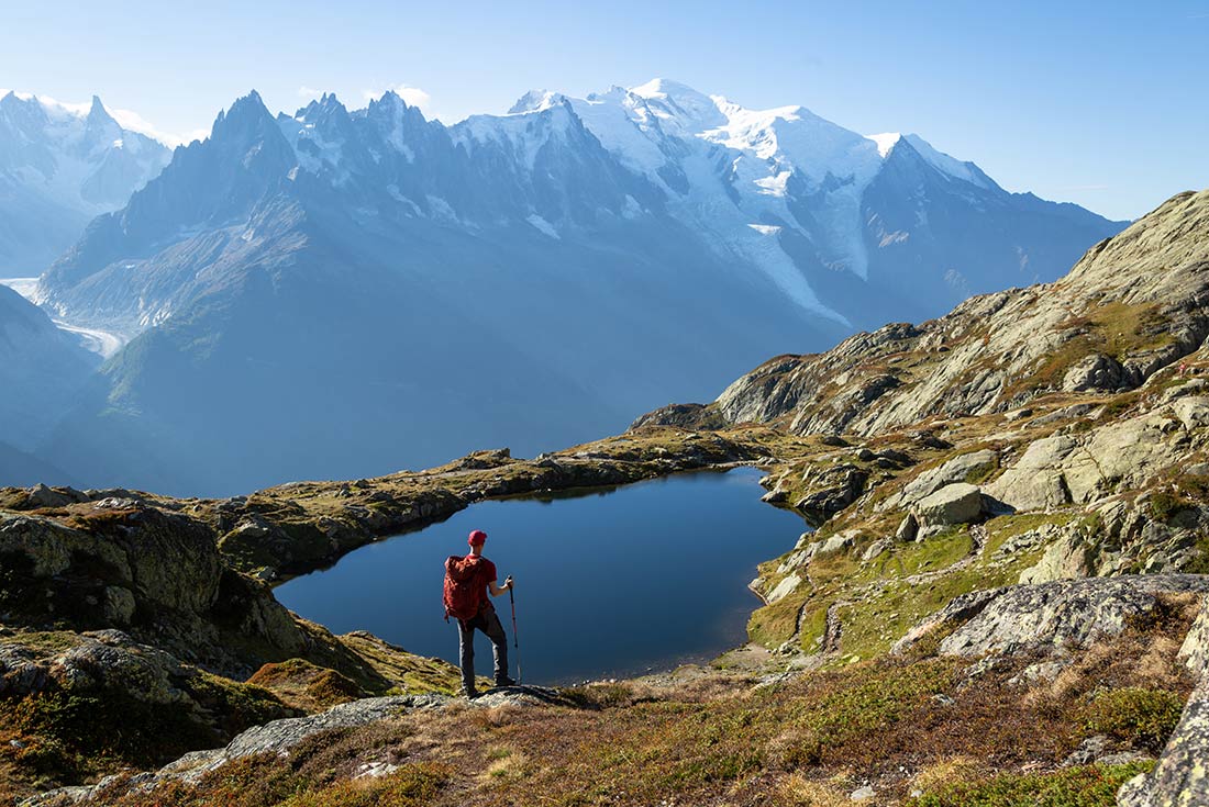Hiker admiring Lac de Cherserys on trail, Tour du Mont Blanc