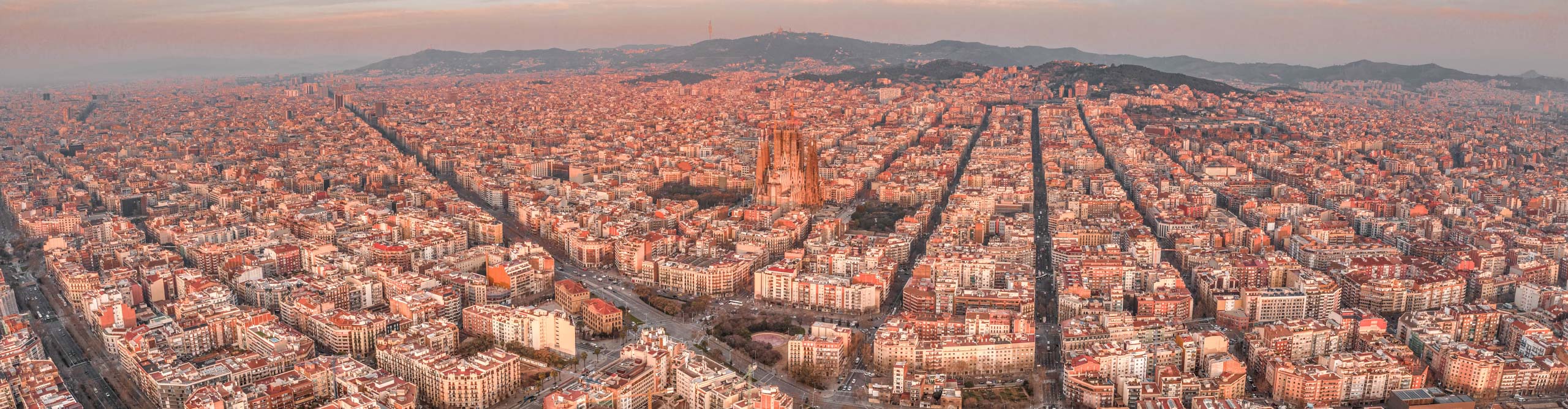 Aerial drone shot of Barcelona city center in morning time with a pink sky
