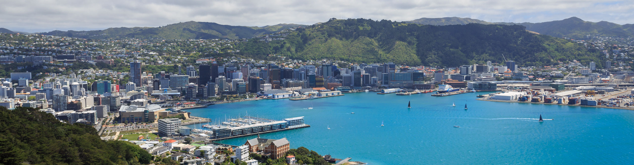 Wellington City harbor and downtown on.a cloudy day, with the water a bright turquoise blue