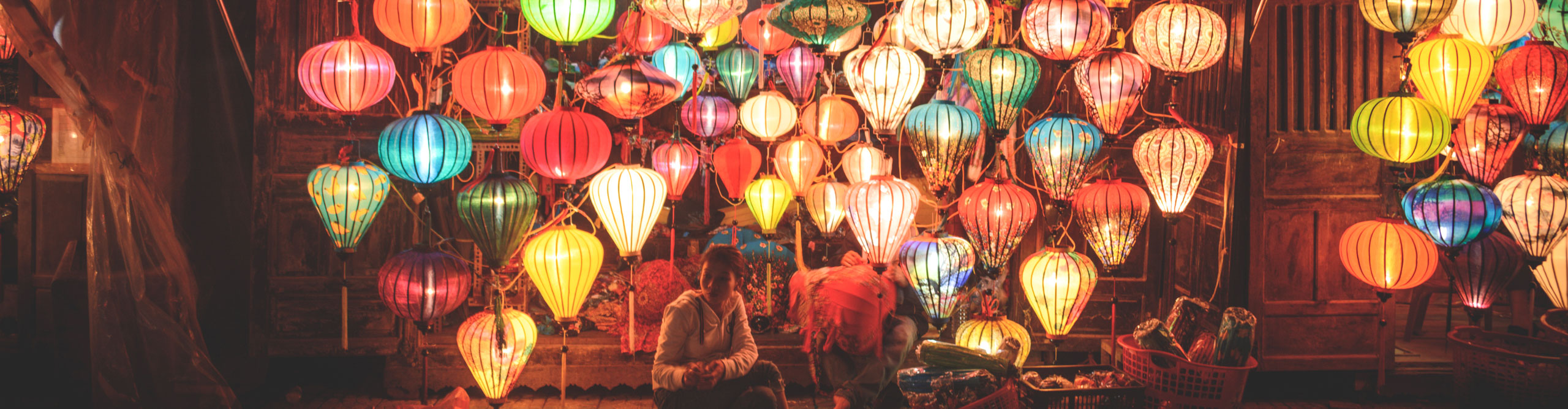 Brightly coloured lanterns lit up on a ceiling in a house in Hoi An, Vietnam 