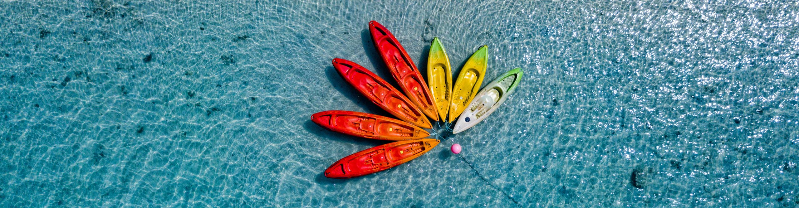 Drone shot of canoes shaped into a flower in the water off the beach off the Cook Islands