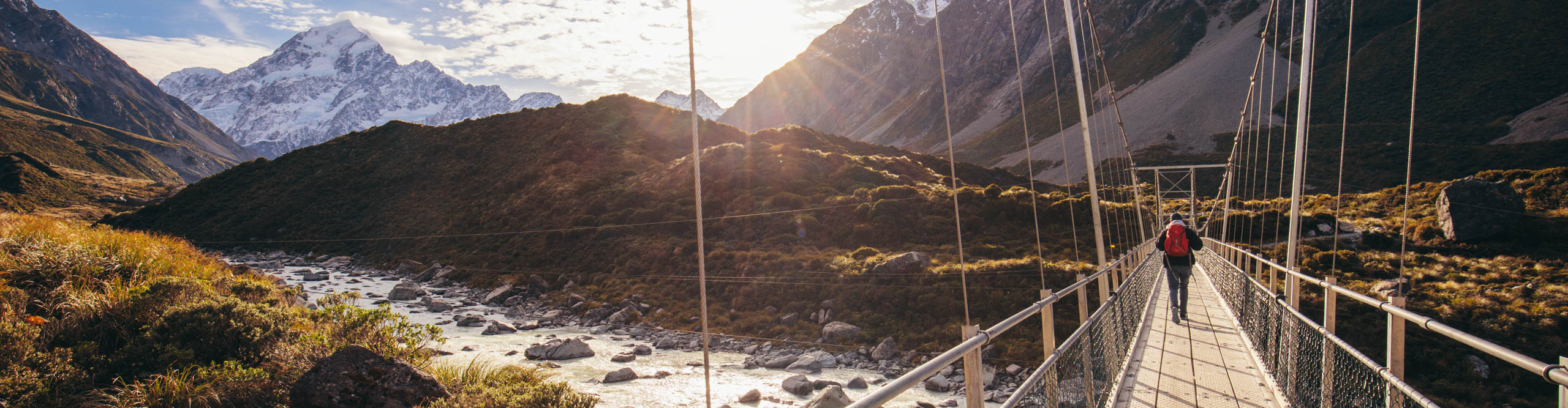 Hiker crossing bridge on the trail to Mount Cook, New Zealand