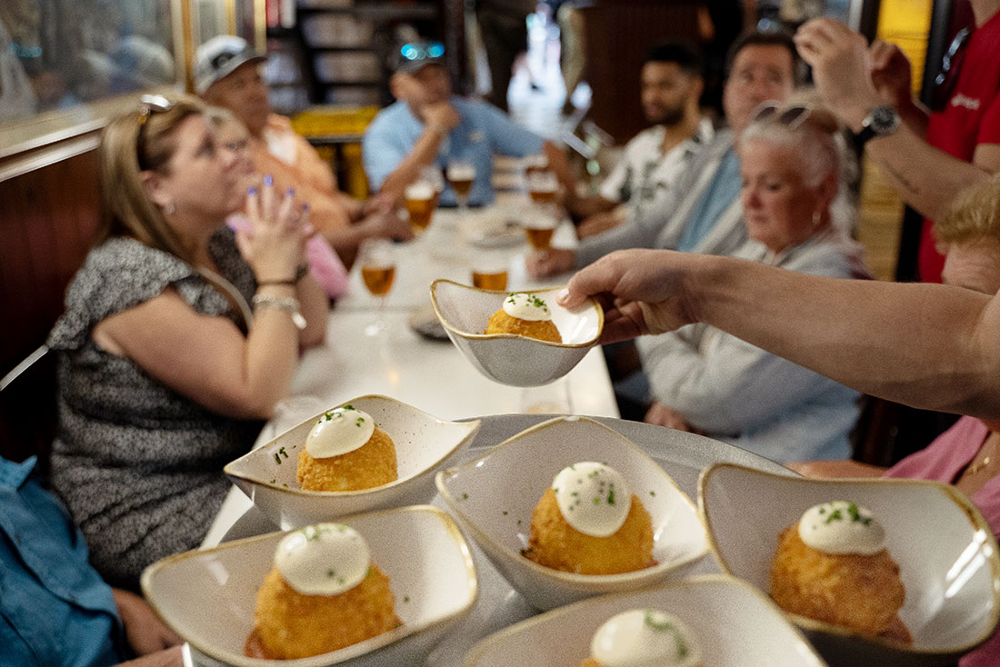 Group of Intrepid travellers being served artfully presented arancini balls in a Bareclona restaurant
