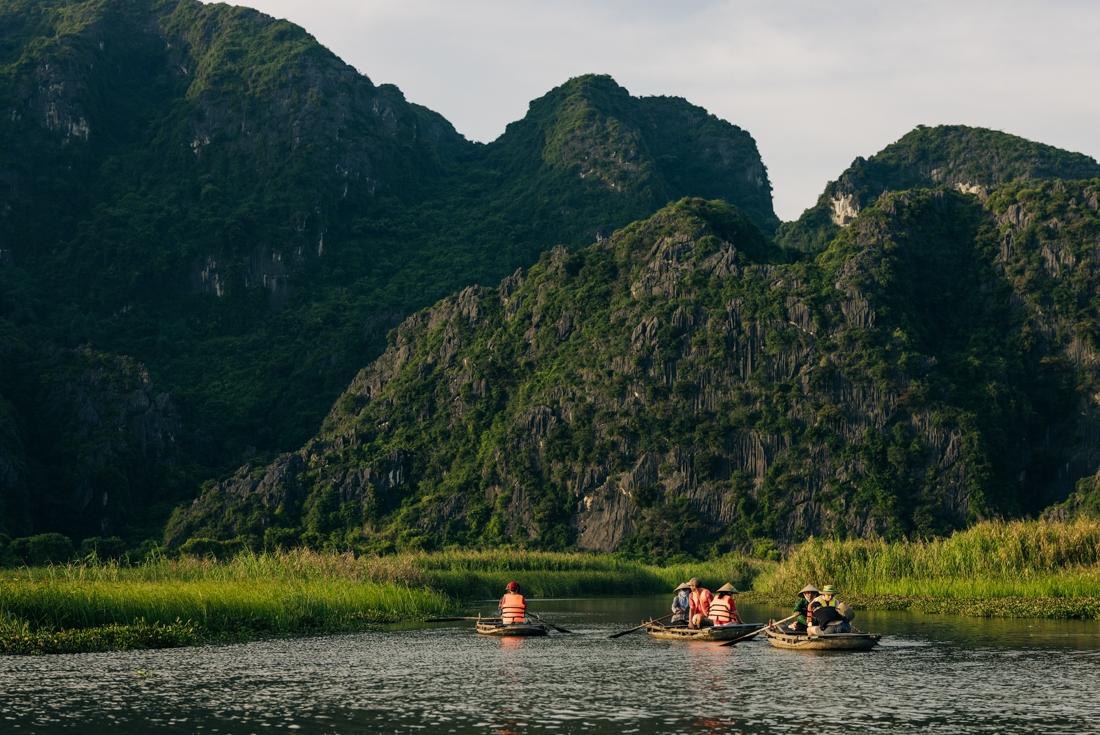 A wide shot of Intrepid travellers and leader on a rowboat tour of Van Long Nature Reserve in Vietnam