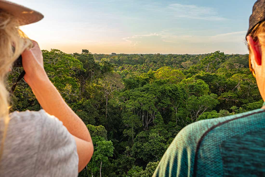 A couple look out across the Amazon Jungle from the comfort of a lookout tower