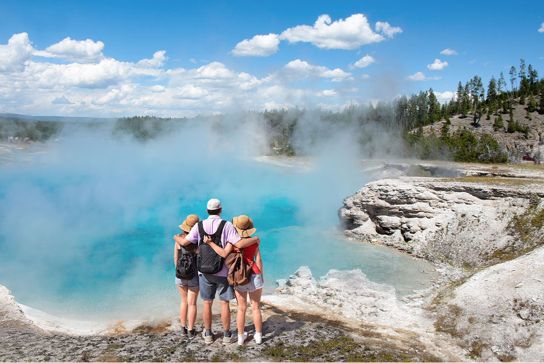 Family admiring geyser in Yellowstone National Park, Wyoming, USA