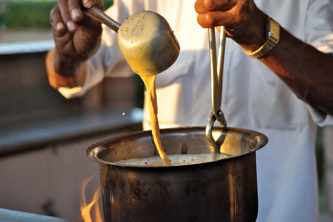 Local vendor mixing hot masala chai, India