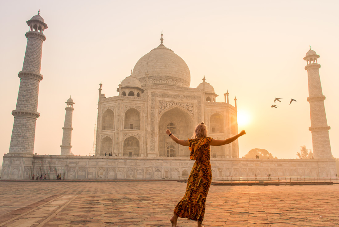 Traveller dancing in front of Taj Mahal at sunrise in India