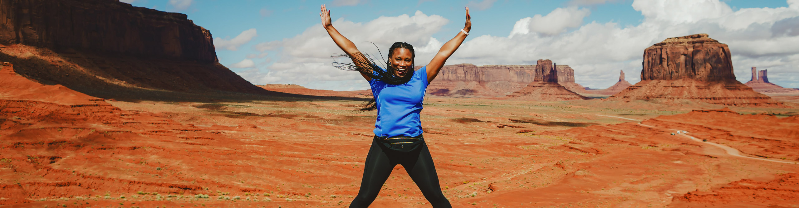 Woman jumping with arms outstretched in the middle of Monument Valley, Arizona, USA