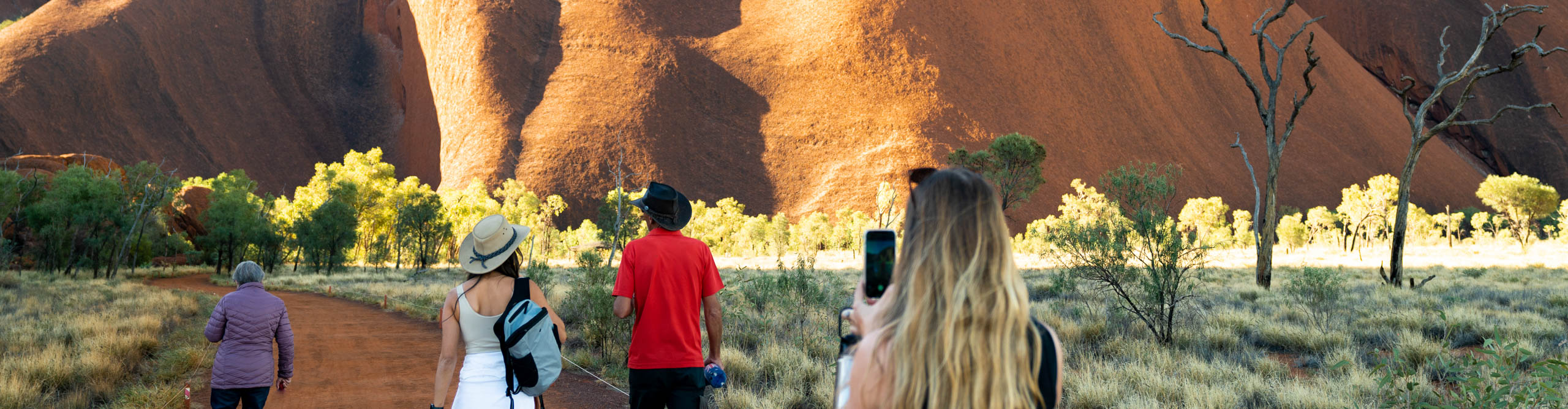 Group walking towards Uluru, in the sunshine, Northern Territory, Australia 