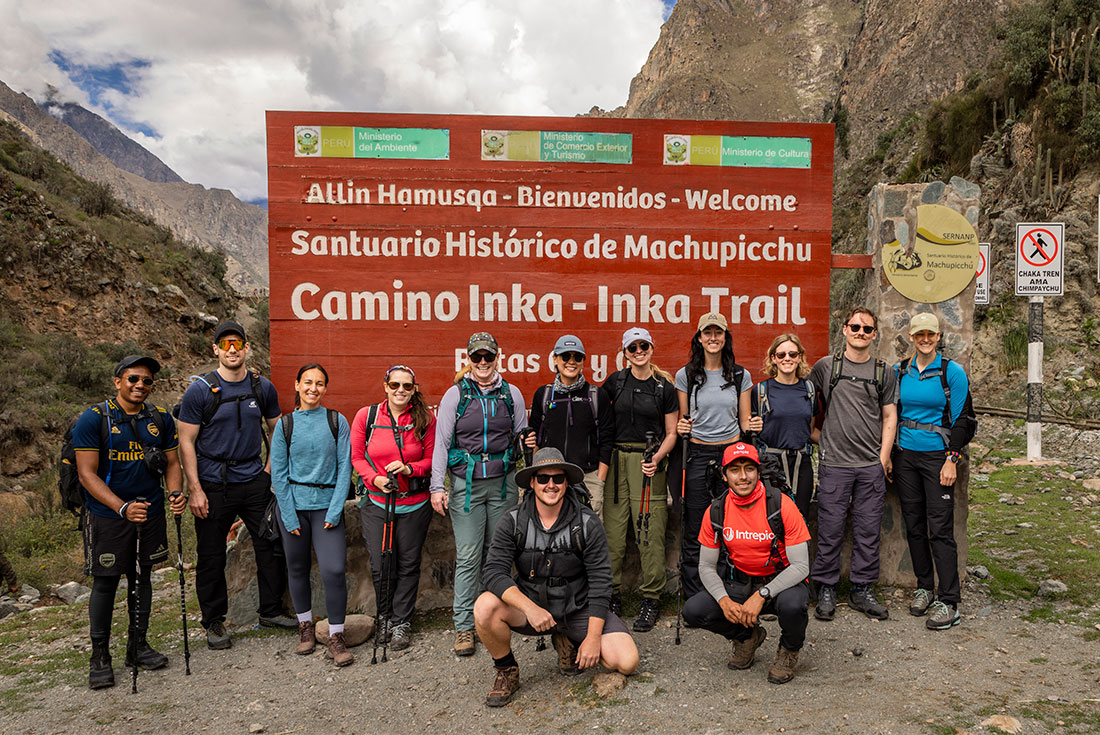 Group of Intrepid travellers pose with sign at the start of the Inca Trail in Peru