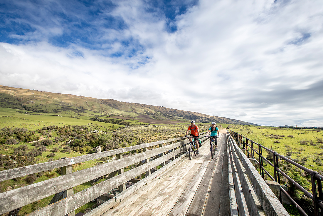 Cycling over a beautiful old bridge on the Otago Central Rail Trail, New Zealand