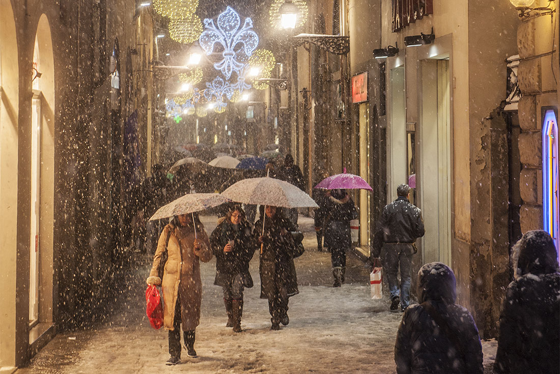 Travellers walk down Via del Corso in Rome amidst a mild snowstorm