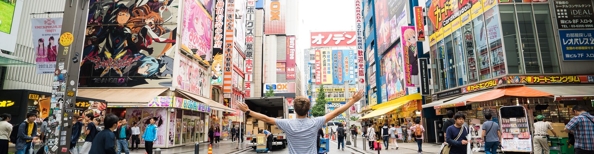 Traveller with arms spread wide in the Akihabara district in Tokyo, Japan