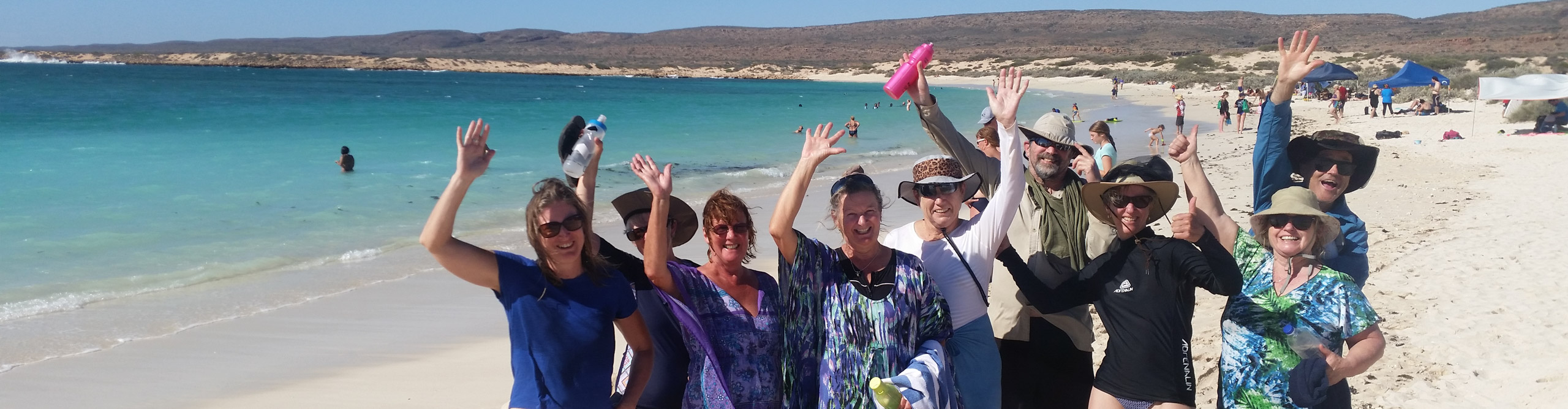 Group on the beach at Ningaloo Reef smiling for the camera on a sunny day, Western Australia 