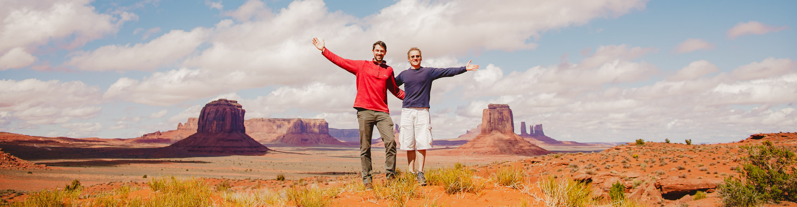 People with arms outstreched for a photo in front of Monument Valley, Arizona 