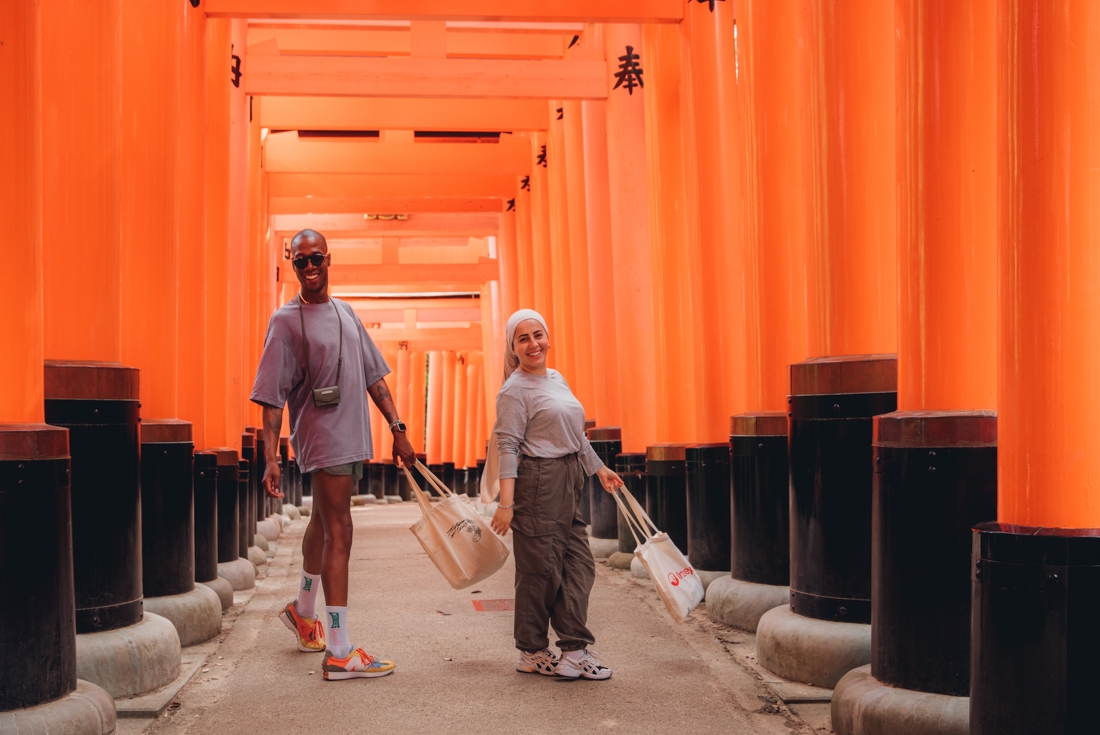Intrepid travellers having fun while exploring Fushimi Inari shrine walking through the orange gates near Kyoto