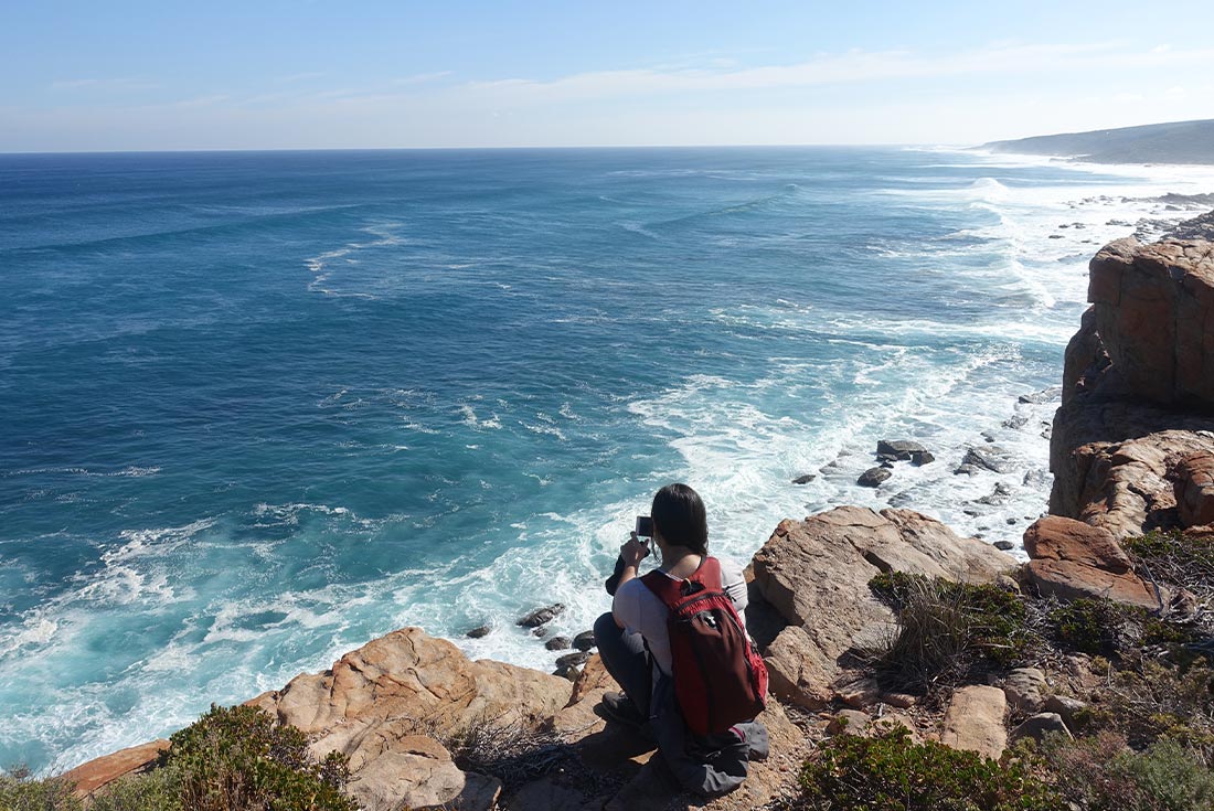 Female traveller taking a picture from Wilyabrup Cliffs along the Cape to Cape track, Australia