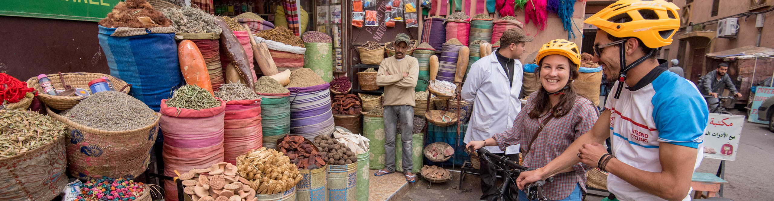 Two travellers on bikes make a stop at a spice market in Marrakech, Morocco 