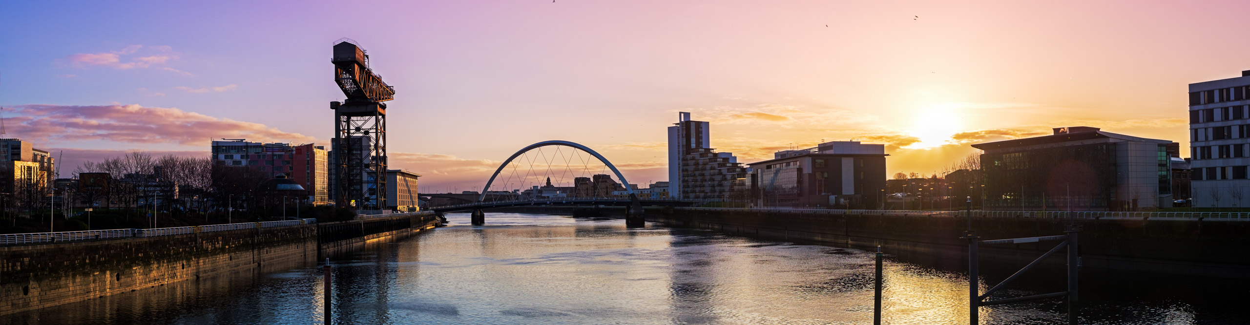View of River Clyde with arched bridge at sunrise with a pink and blue sky, Glasgow, Scotland