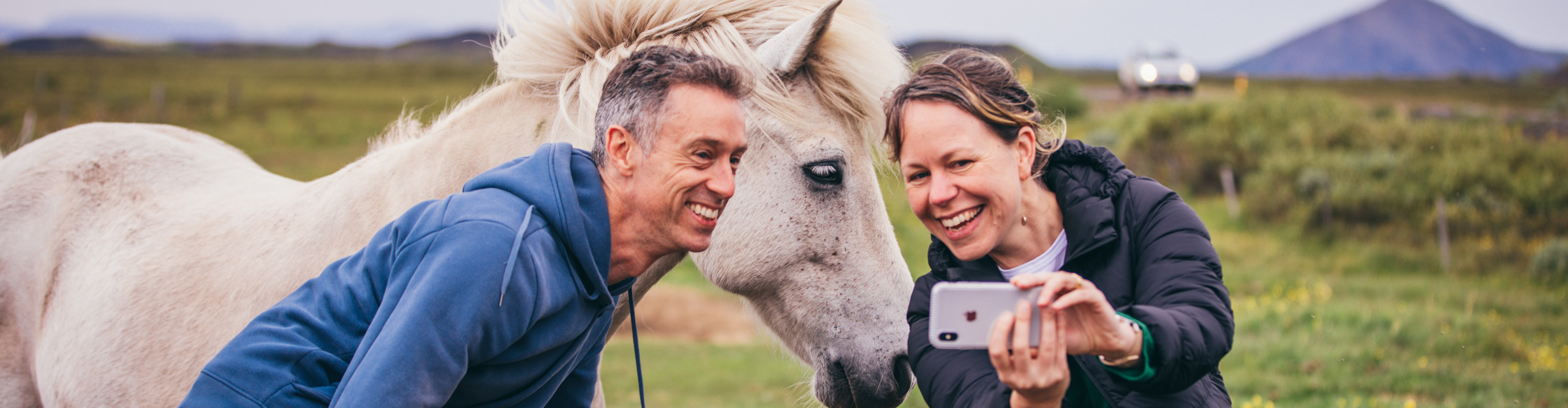 People taking selfie with a pony in a field in Iceland