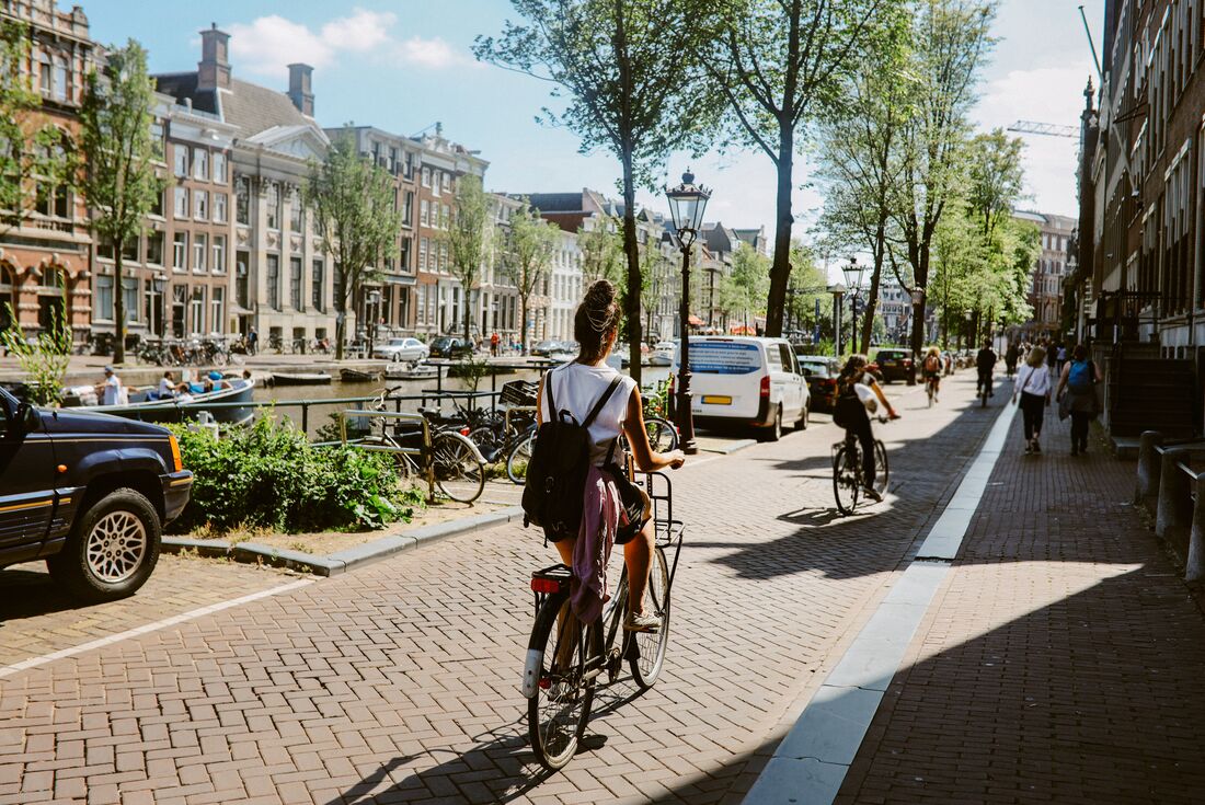 Travellers ride bikes alongside the canals of Amsterdam