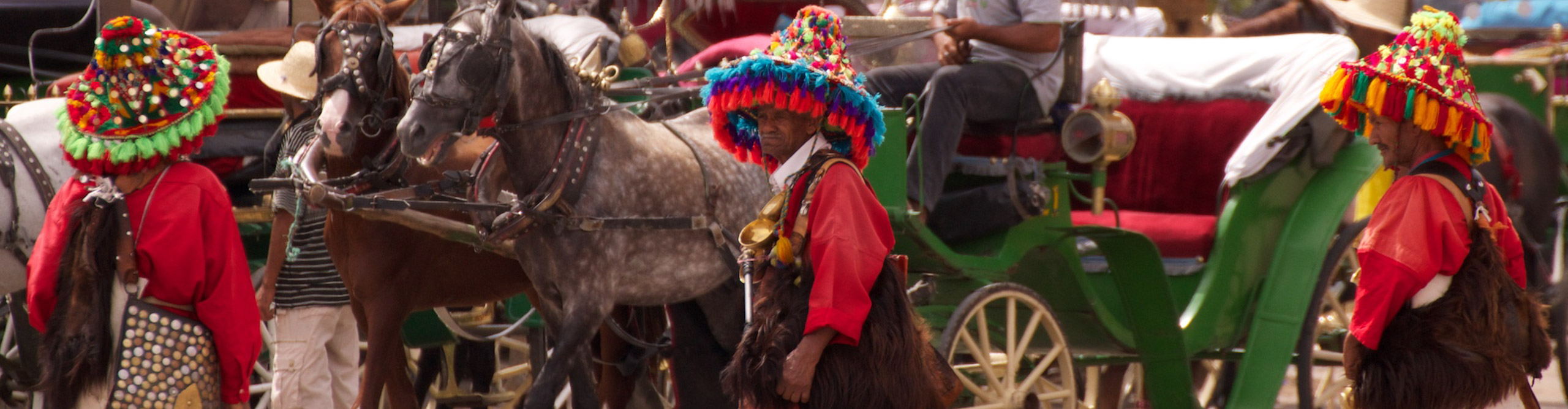 Men in traditional clothes and headwear standing with horses in Morocco 