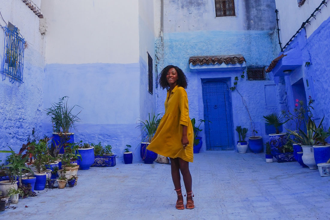 Female traveller posing among the bright blue walls in Chefchaouen, Morocco