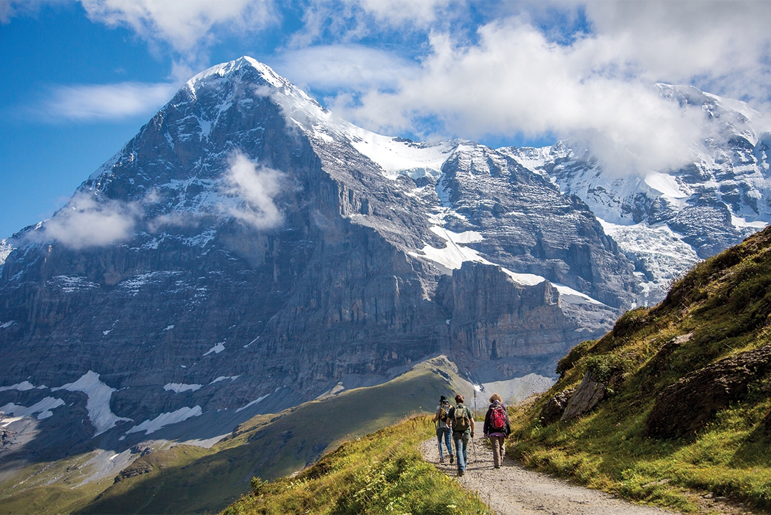 A group of three hikers approach Eiger, hiking in the Alps near Lauterbrunnen